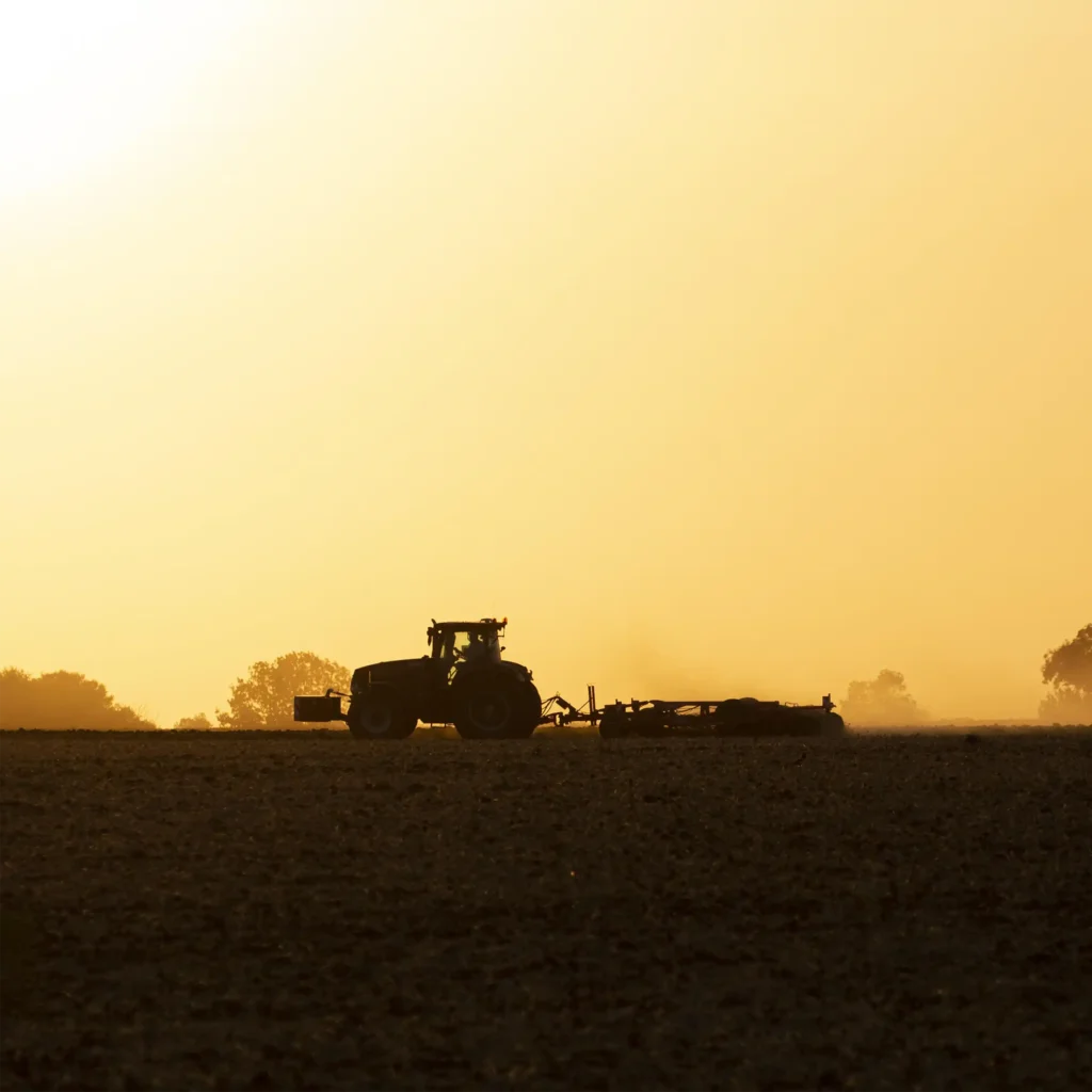 A Chowns Agricultural Services A tractor plowing a field at sunset in Warwickshire.