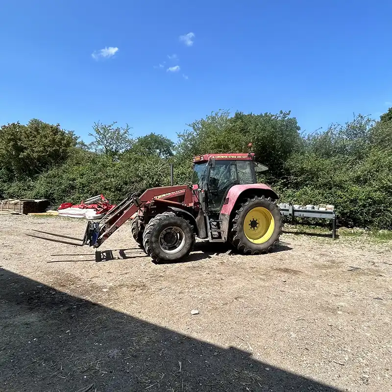 A Chowns Agricultural Services A farming tractor is parked in a dirt lot.
