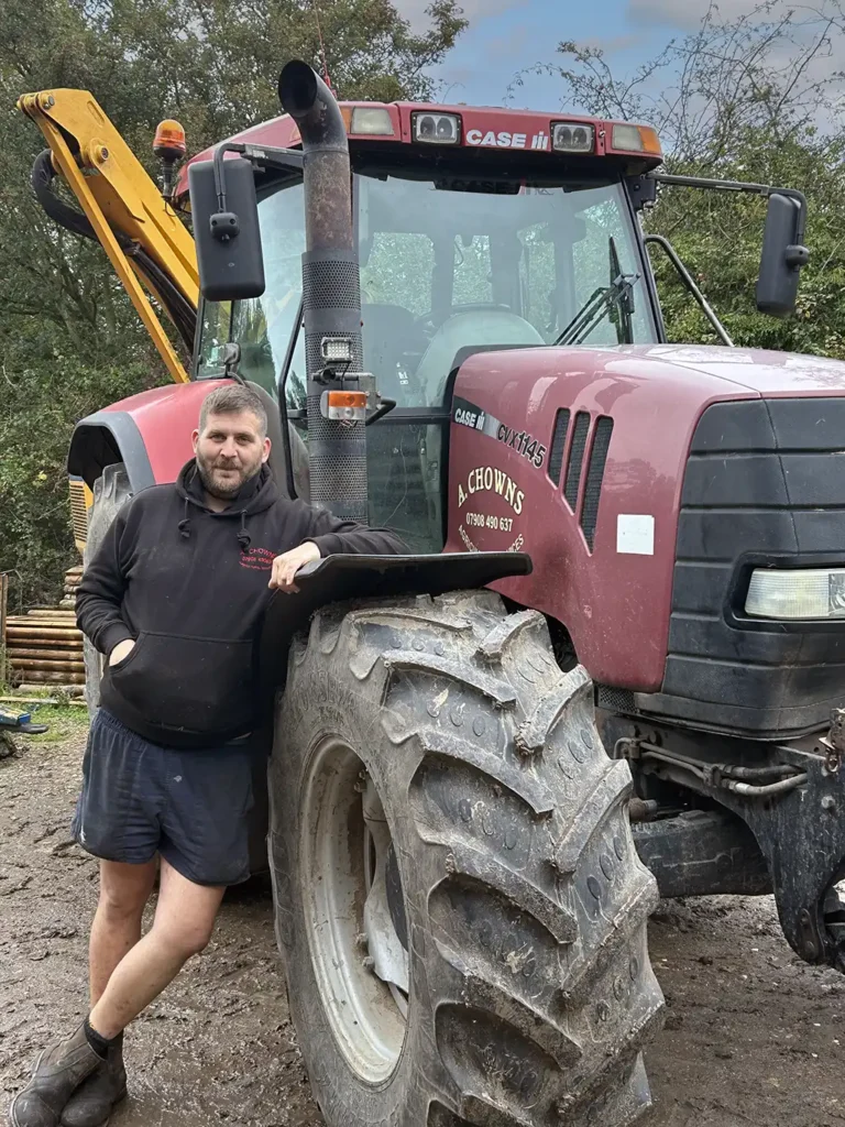 a-chowns-agricultural-services Adam Miller standing next to a large tractor.