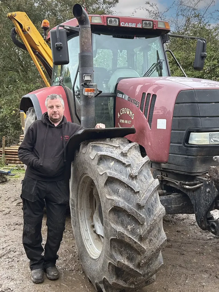 a-chowns-agricultural-services Andrew Chowns man standing next to a tractor with large tires.