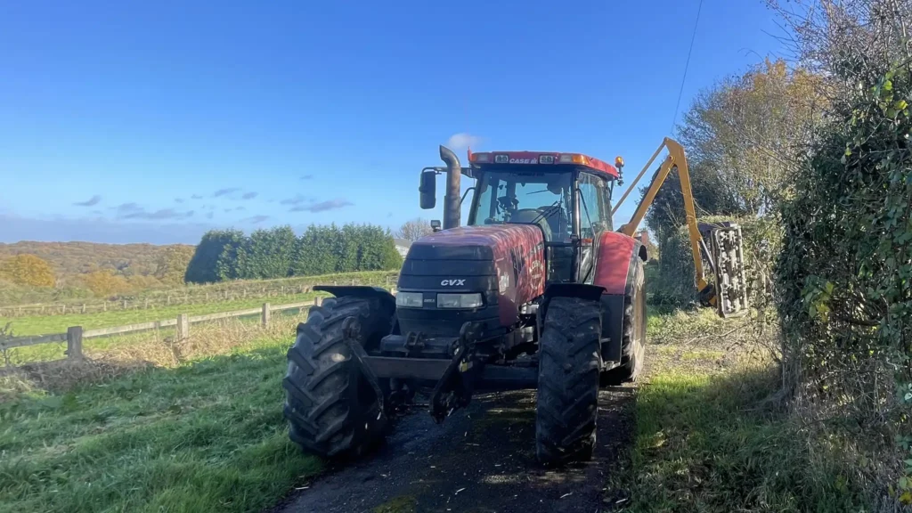 a-chowns-agricultural-services A red tractor driving down a country road.